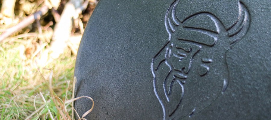 Close-up van deksel gietijzeren pan met logo van Valhal Outdoor.
